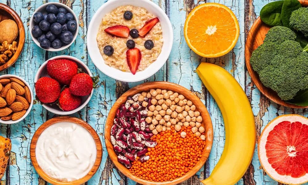 An assortment of nutritious foods including fruit, nuts, legumes, oats, yoghurt and broccoli